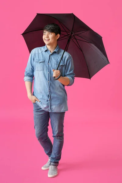 Renkli arka planda şemsiye ile Yakışıklı Asyalı adam — Stok fotoğraf
