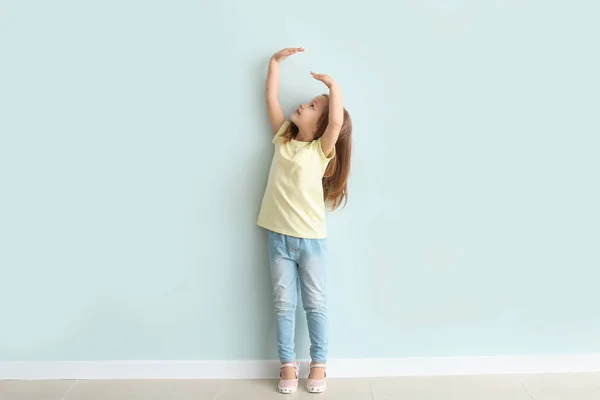 Милая маленькая девочка, измеряющая свой рост у стены — стоковое фото