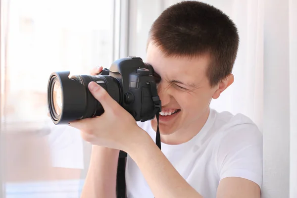 Nastoletni chłopiec z aparatem fotograficznym w pobliżu okna — Zdjęcie stockowe
