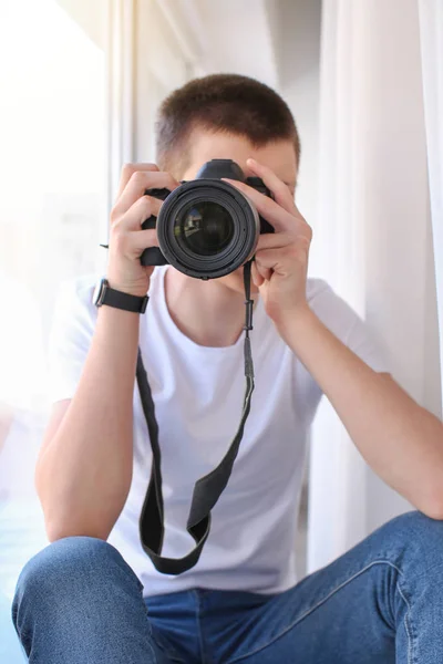 Nastoletni chłopiec z aparatem fotograficznym w pobliżu okna — Zdjęcie stockowe