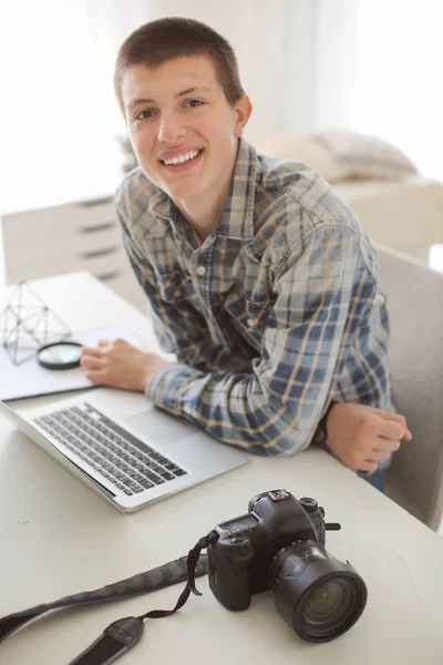 Tiener jongen met fotocamera en laptop thuis — Stockfoto