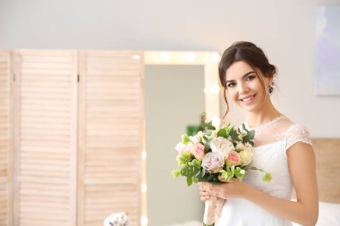 Beautiful young bride with bouquet of flowers at home clipart