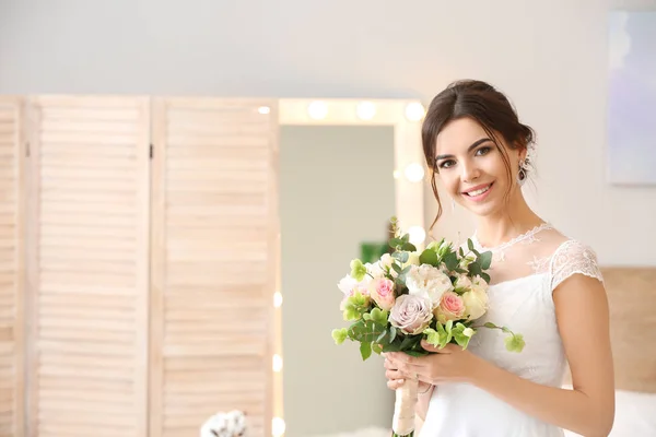 Beautiful young bride with bouquet of flowers at home — Stock Photo, Image