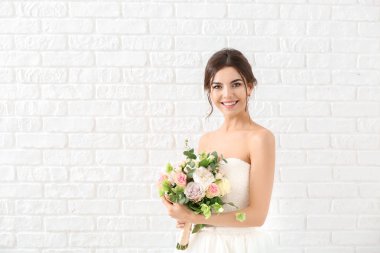 Beyaz tuğla arka plan üzerinde çiçek buketi ile güzel genç gelin