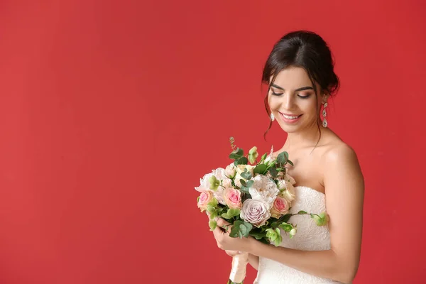 Schöne junge Braut mit Blumenstrauß auf farbigem Hintergrund — Stockfoto