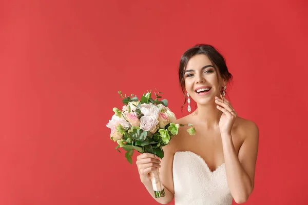 Schöne junge Braut mit Blumenstrauß auf farbigem Hintergrund — Stockfoto