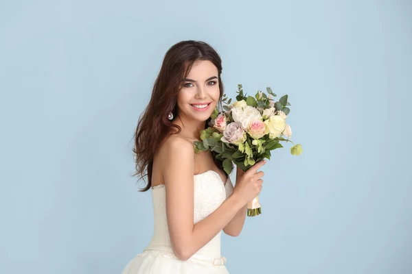 Schöne junge Braut mit Blumenstrauß auf farbigem Hintergrund — Stockfoto