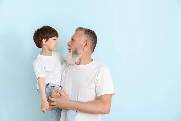 Cute little boy with grandfather on light background — Stock Photo, Image
