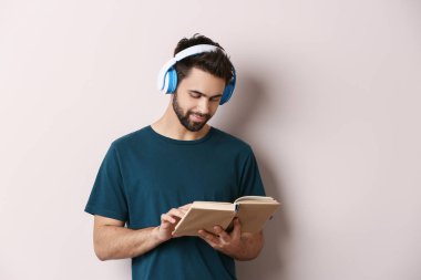 Genç adam müzik dinleme ve ışık arka plan üzerinde kitap okuma