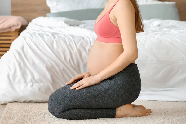 Young pregnant woman in sportswear at home — Stock Photo, Image