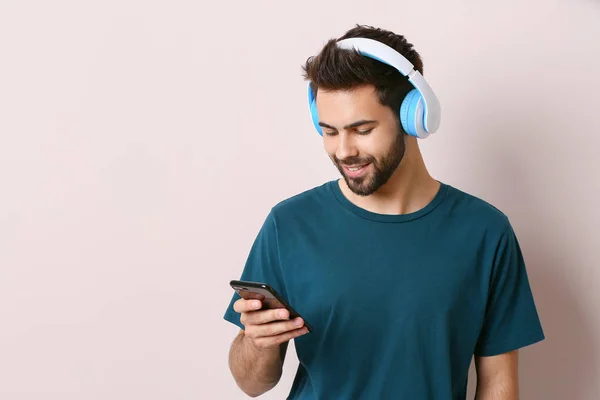 Young man listening to audiobook on light background — Stock Photo, Image