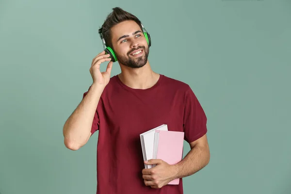 Young man listening to audiobook on color background — Stock Photo, Image