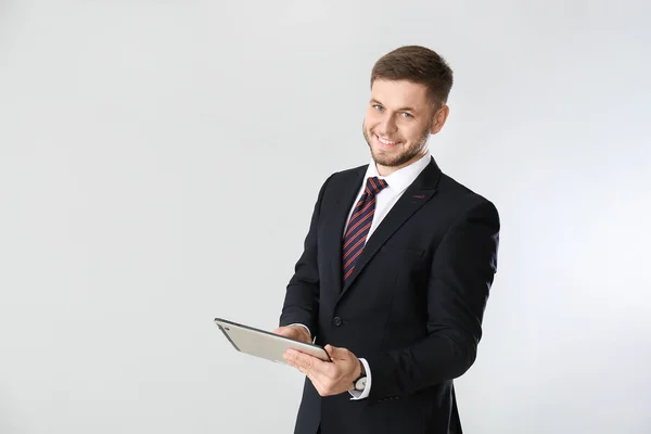 Hombre de negocios guapo con Tablet PC sobre fondo claro — Foto de Stock