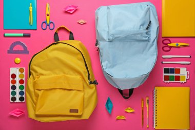 Renkli arka planda okul sırt çantaları ve kırtasiye