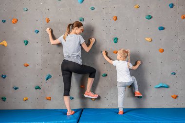 Genç kadın ile onu küçük kız tırmanma duvar içinde spor salonu