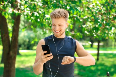 Sportif genç adam nabzını dışarıda kontrol ediyor