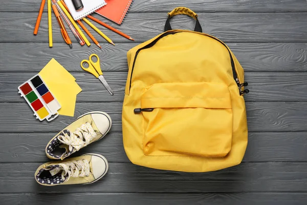 Mochila escolar, zapatos y artículos de papelería sobre fondo de madera — Foto de Stock