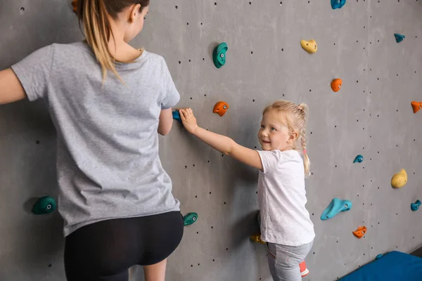 Young woman with her little daughter climbing wall in gym — Stock Photo, Image