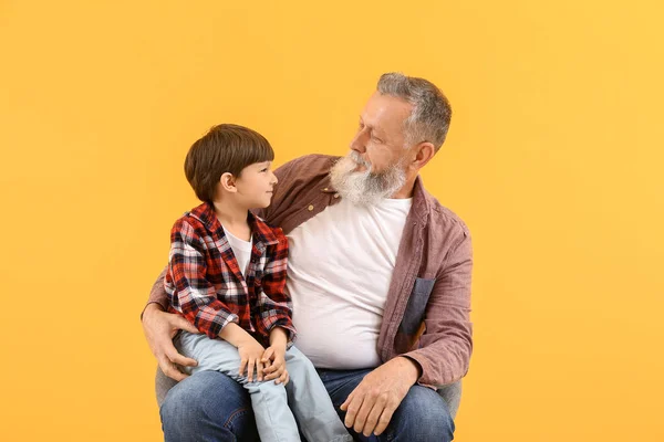 Cute little boy with grandfather on color background — Stock Photo, Image