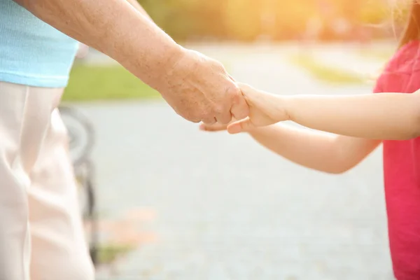 Cute little girl with grandmother holding hands outdoors — Stock Photo, Image