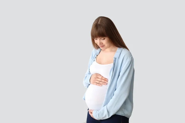 Молода вагітна жінка на світлому фоні — стокове фото