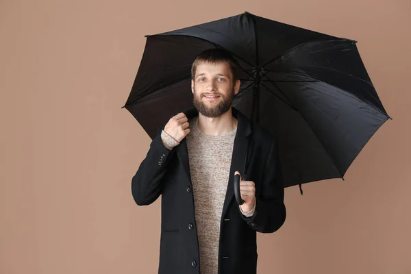 Handsome man with umbrella on color background — Stock Photo, Image