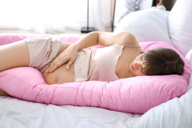 Hamile yastığı evde uyuyan genç hamile kadın