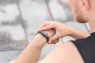 Sportif genç adam nabzını dışarıda kontrol ediyor