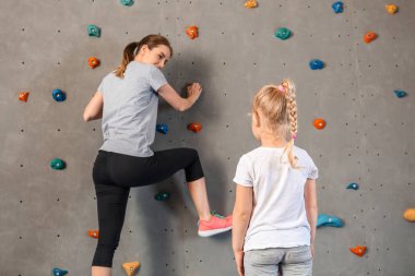 Genç kadın ile onu küçük kız tırmanma duvar içinde spor salonu