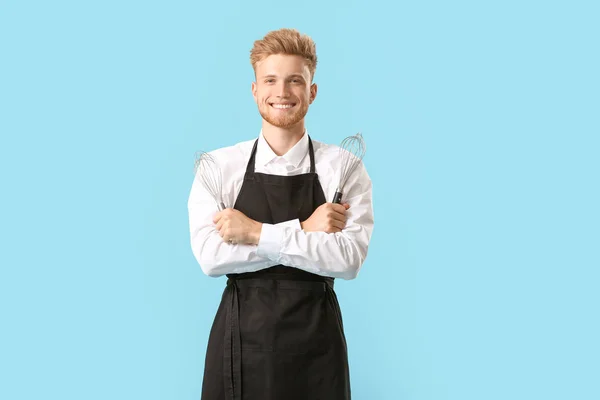 Handsome male chef with whisks on color background — Stock Photo, Image