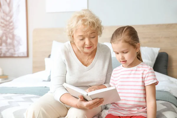 Linda niña leyendo libro con la abuela en casa —  Fotos de Stock