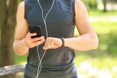 Sportif genç adam nabzını dışarıda kontrol ediyor