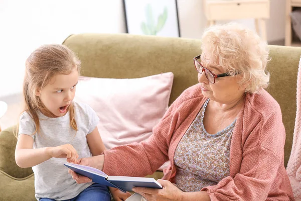 Χαριτωμένο μικρό κορίτσι διαβάζοντας το βιβλίο με τη γιαγιά στο σπίτι — Φωτογραφία Αρχείου