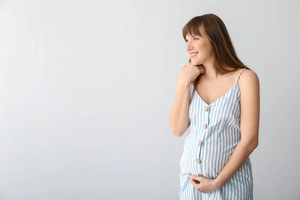 Jonge zwangere vrouw op lichte achtergrond — Stockfoto