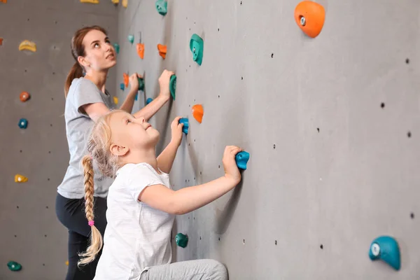 Jovem com sua filha escalando parede no ginásio — Fotografia de Stock