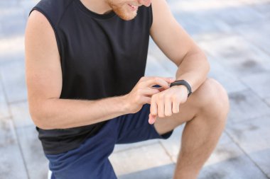 Sportif genç adam nabzını dışarıda kontrol ediyor