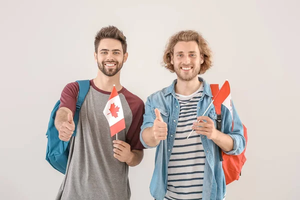 Young male students with Canadian flags on light background — Stock Photo, Image