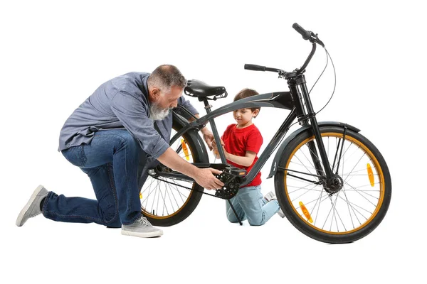 Cute little boy with grandfather repairing bicycle on white background — Stock Photo, Image