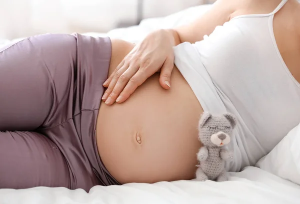 Mladá těhotná žena odpočívá v ložnici — Stock fotografie