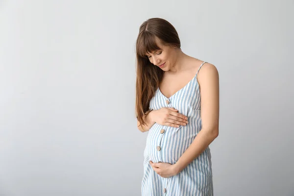 Молодая беременная женщина на светлом фоне — стоковое фото