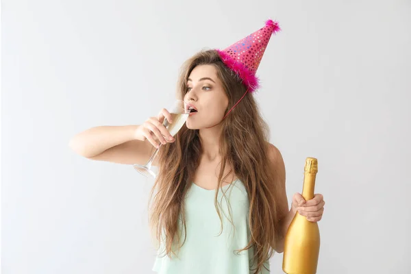 Mulher bêbada com chapéu de festa e champanhe no fundo claro — Fotografia de Stock