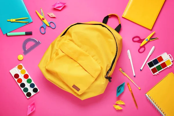 Schulrucksack und Schreibwaren auf farbigem Hintergrund — Stockfoto