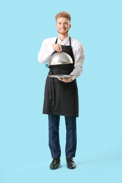 Красивий чоловічий шеф-кухар з підносом та шафою на кольоровому фоні — стокове фото
