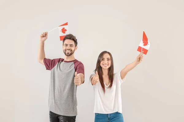 Молоді люди з канадськими прапорами на світлому фоні — стокове фото