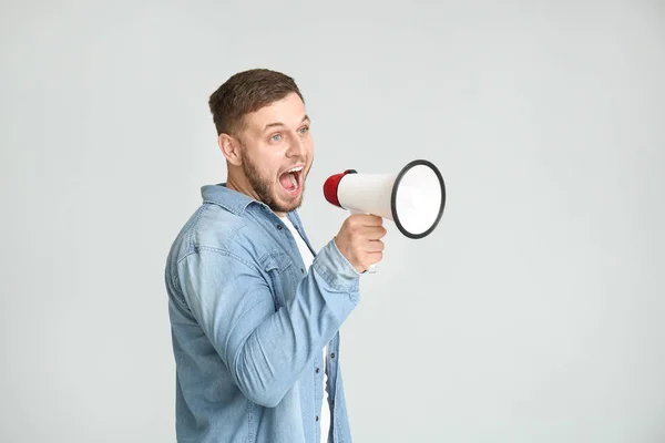 Jonge man met een megafoon op lichte achtergrond — Stockfoto