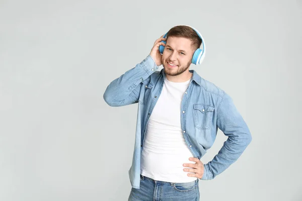 Stilig ung man lyssnar på musik på ljus bakgrund — Stockfoto