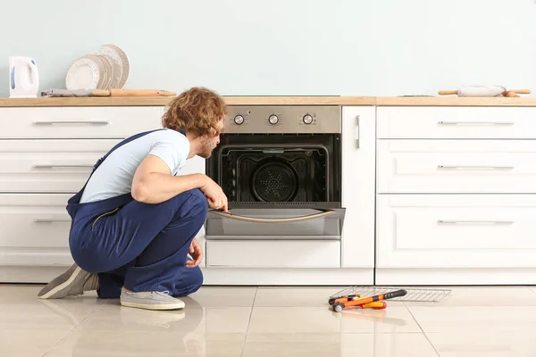 Arbeiter repariert Ofen in Küche — Stockfoto