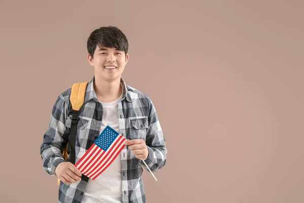Young Asian student with USA flag on color background — Stock Photo, Image