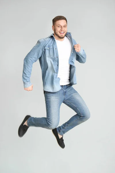 Handsome jumping young man on light background — Stock Photo, Image