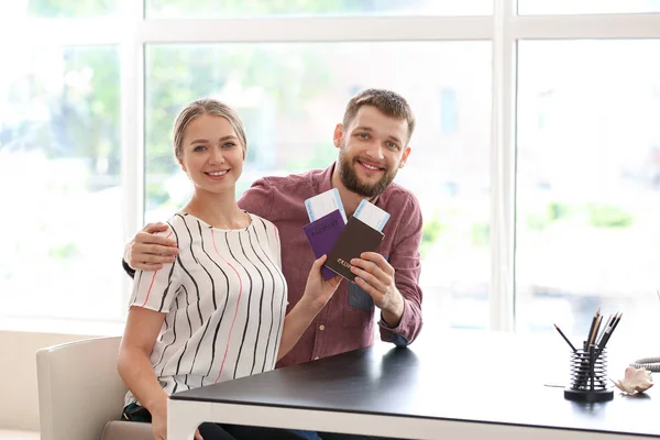 Happy couple with passports and tickets in travel agency — Stock Photo, Image